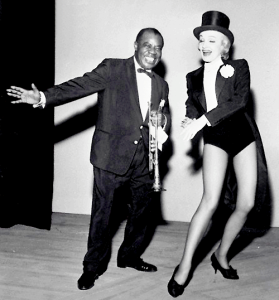 Marlene Dietrich muove qualche passo di danza con il grande Sachmo, Louis Armstrong.