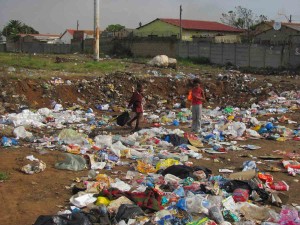 Bambini cercano e giocano tra i rifiuti: si intravede un quartiere abitativo...