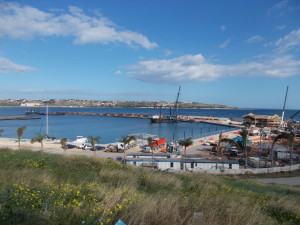 Si lavora nei primi giorni del 2018. A dx la struttura riconoscibile della club house, sul mare il grande pontone che sta affrettando la rifinitura dei moli, delle banchine e dei pontili in muratura.