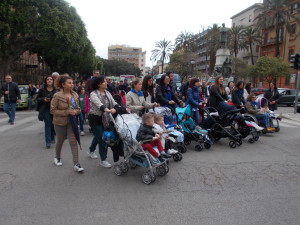 Mamme con bimbi alla partenza dalle "Croci". Oltre alle carrozzelle "piene", una vuota simbolo dei bambini mai nati.