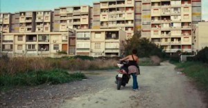 Un ragazzo spinge lo scooter in panne, percorrendo una scorciatoia verso casa. L'immagine si apre avarie interpretazioni. Allegra non è. Il quartiere è Librino.