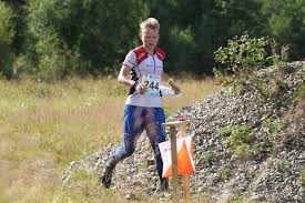 Orinteering di alto livello: l'atleta corre in cross country. Ha in tasca bussola e cartina e compasso.